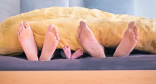 Family sleeping in bed after big meal
